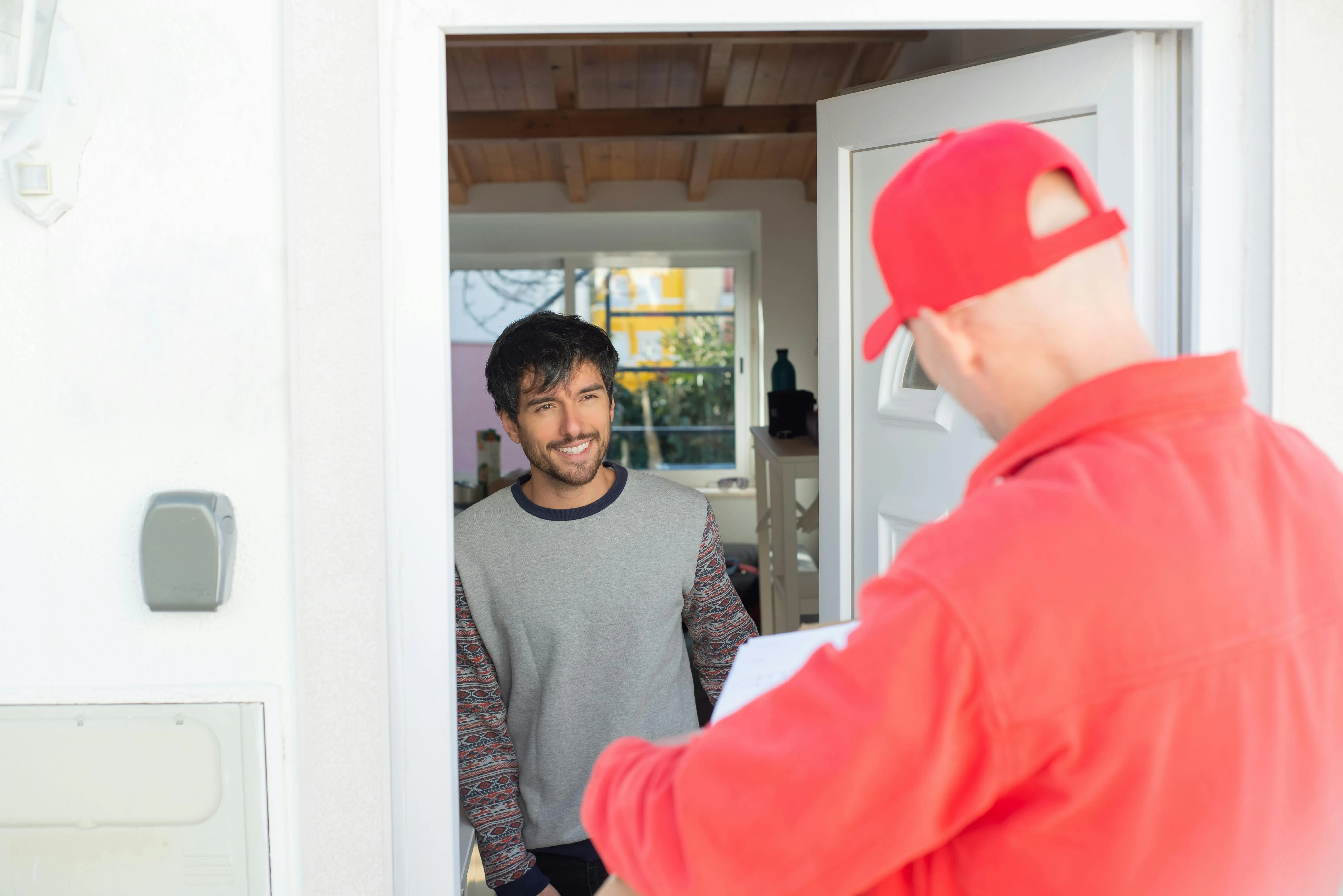 Homem feliz recebe entrega de comida ou produto em casa de entregador.