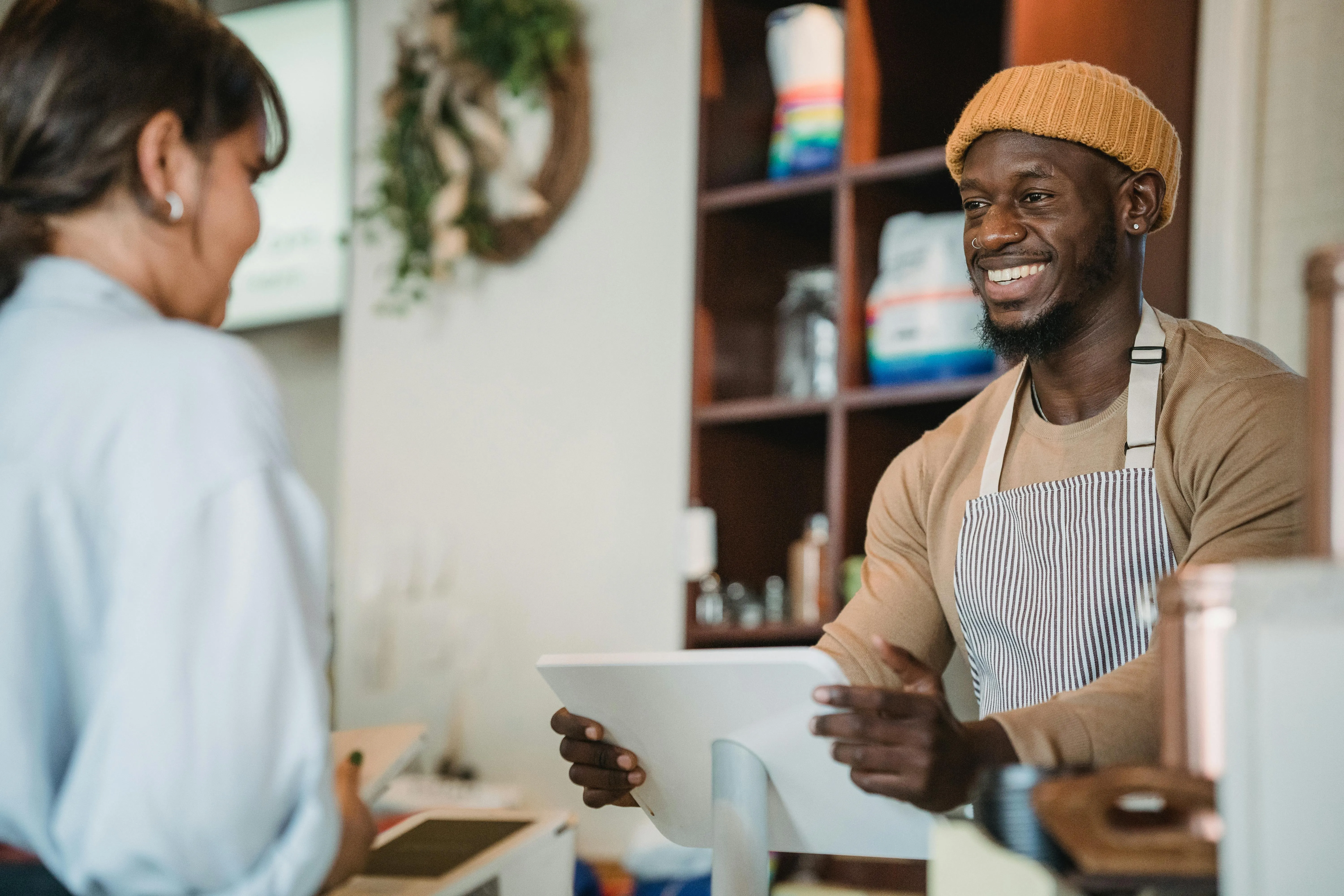 Homem sorridente atende cliente em loja, criando experiência de compra positiva.