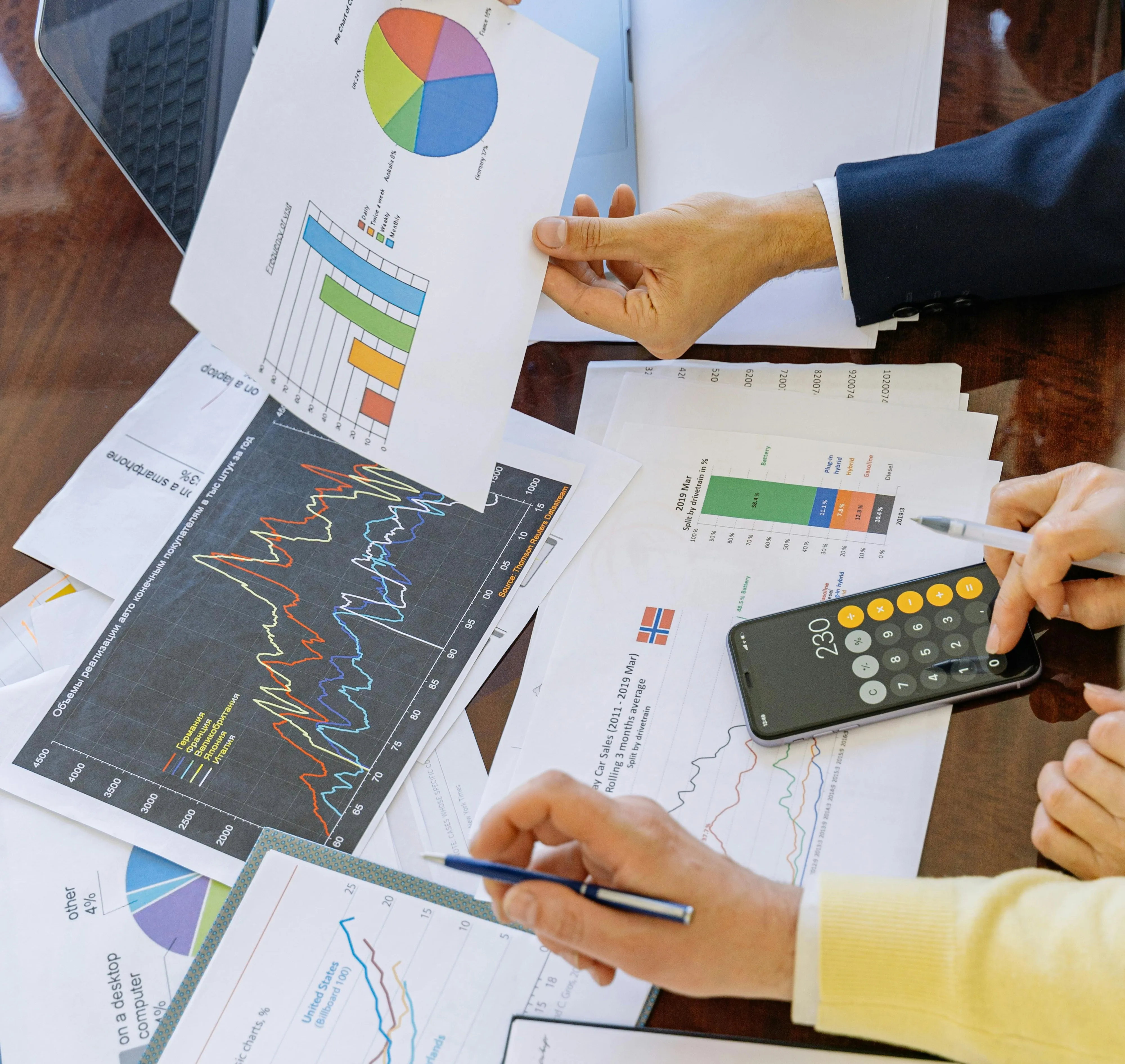 #FotoDescrição: Mãos analisando gráficos, planilhas e calculadora sobre uma mesa, representando planejamento financeiro e estratégia de negócios.