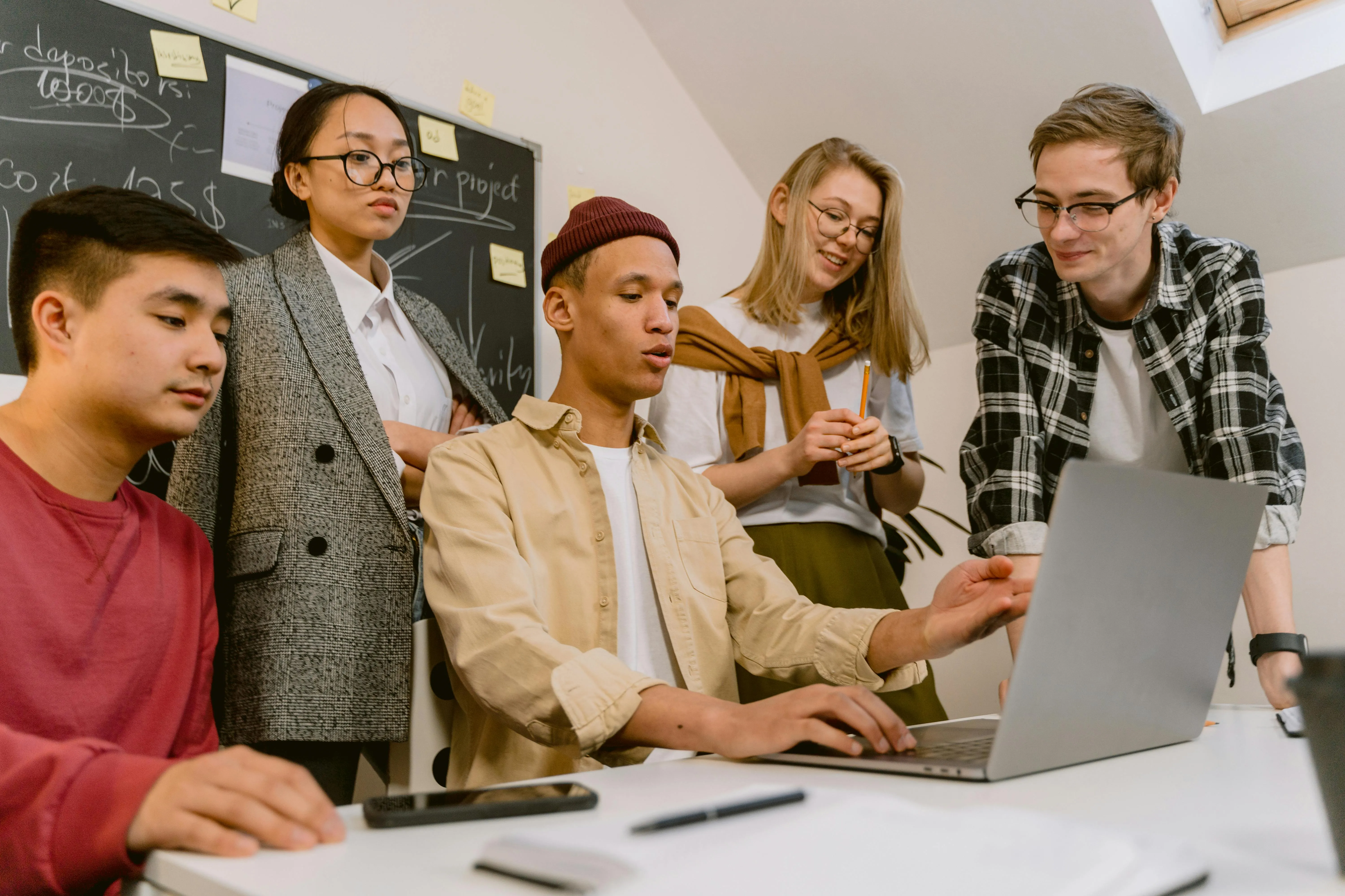 Grupo de jovens trabalhando juntos em um projeto, observando um laptop.