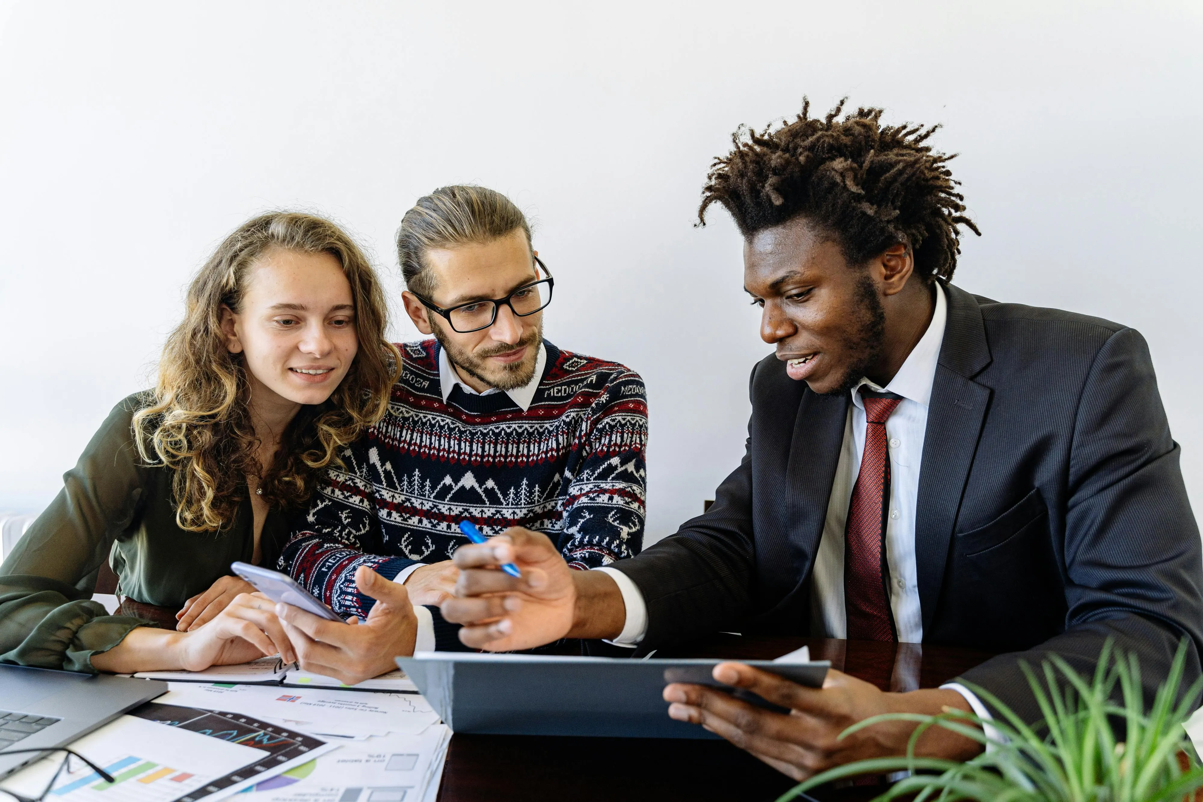 #FotoDescrição: Três pessoas reunidas em uma mesa de escritório, analisando dados e gráficos enquanto discutem estratégias de fidelização no setor automotivo.