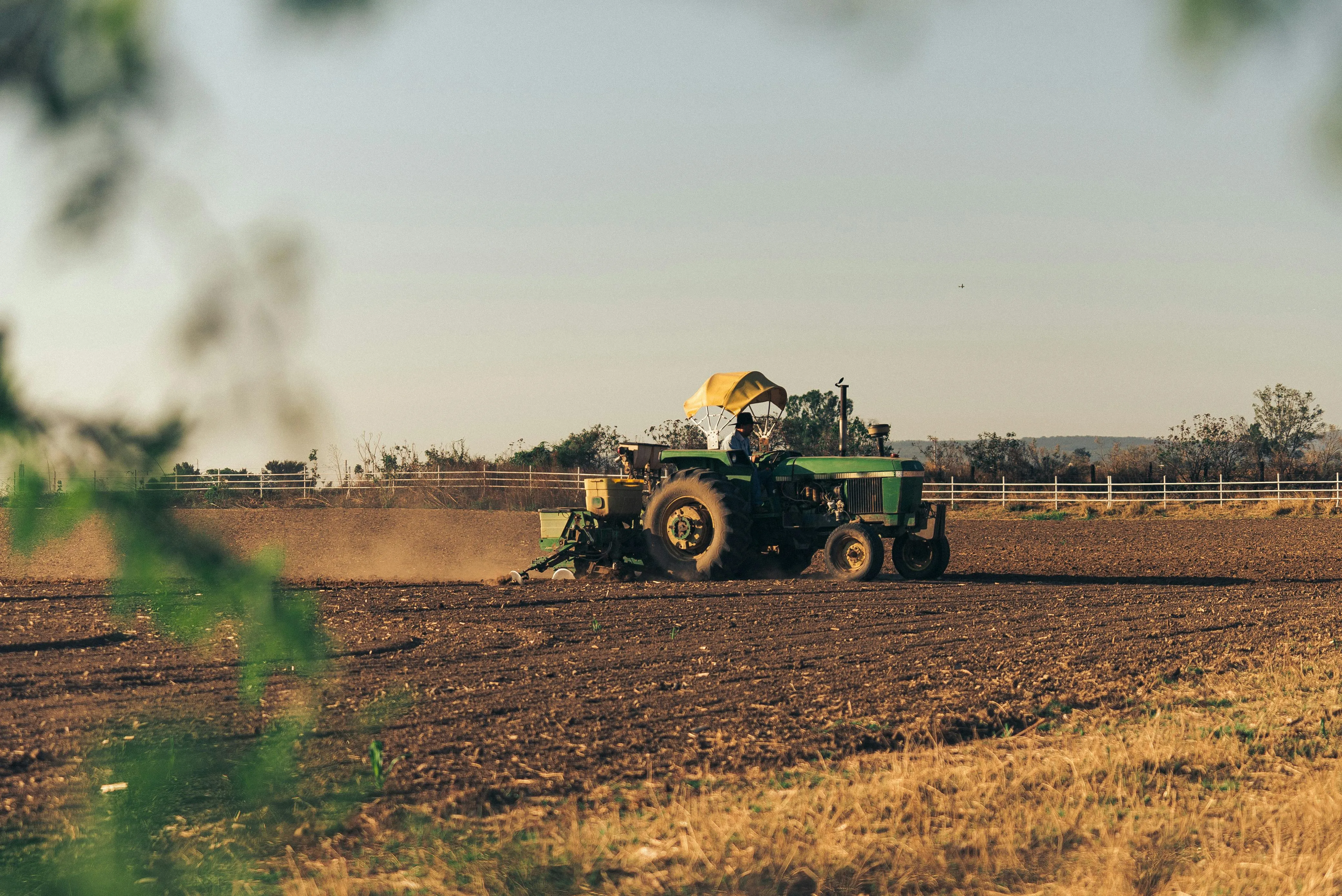 Trator arando a terra em uma plantação ao entardecer