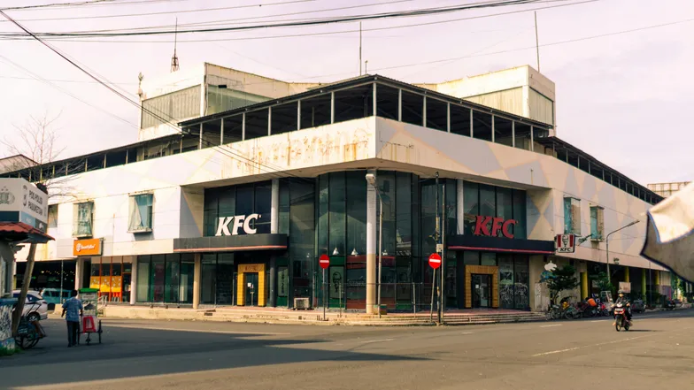 Fachada de prédio com restaurante KFC em esquina de rua movimentada.