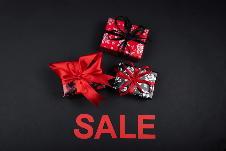 Caixas de presente decoradas sobre fundo preto com a palavra sale.