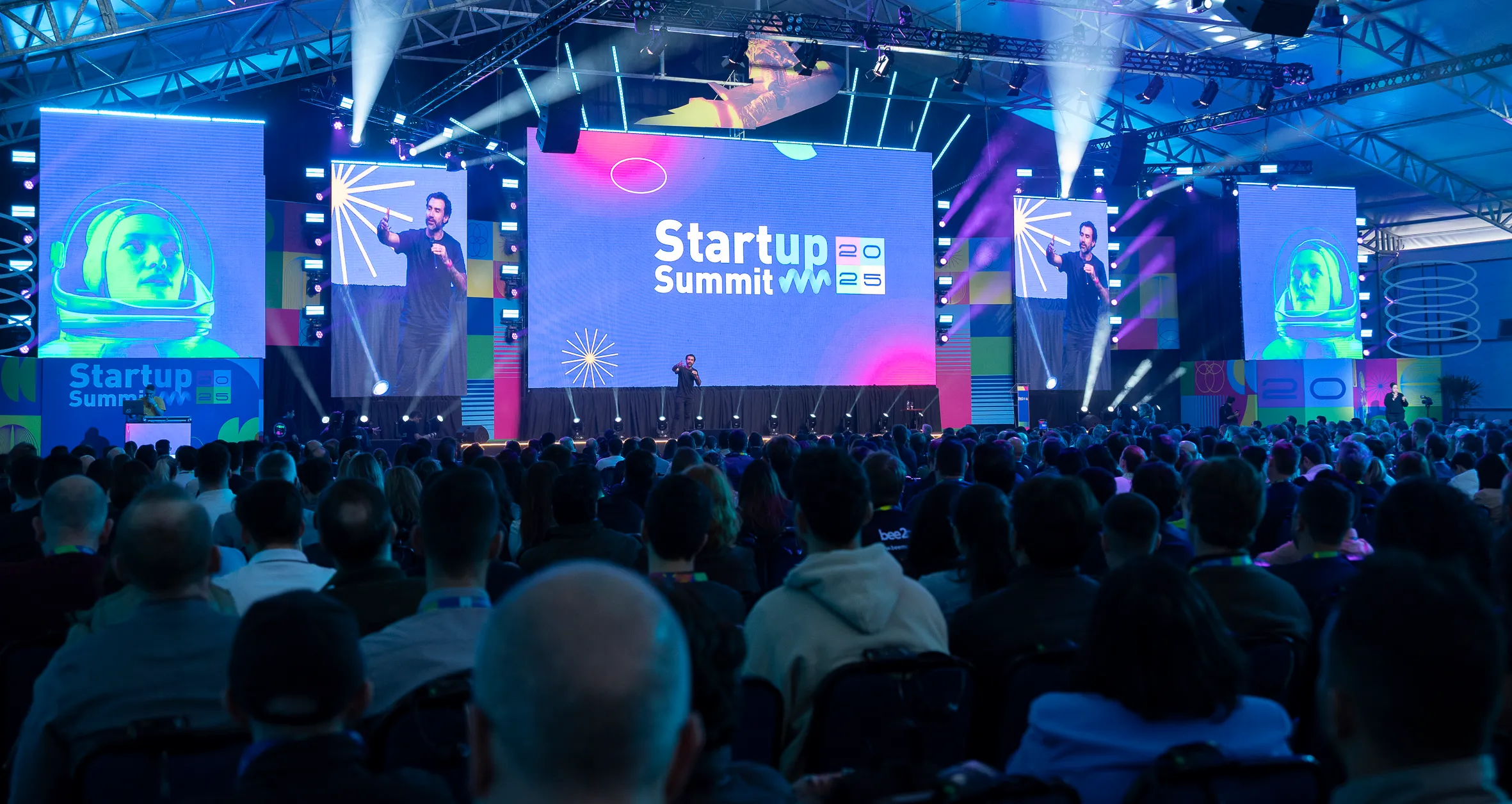 #FotoDescrição: Auditório cheio no Startup Summit 2025 com palco iluminado.